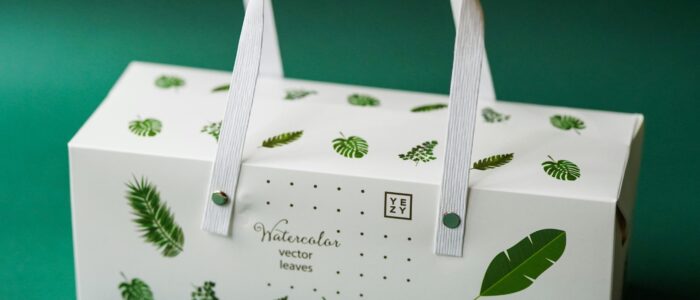 Elegant packaging box featuring watercolor leaf design on a green background.